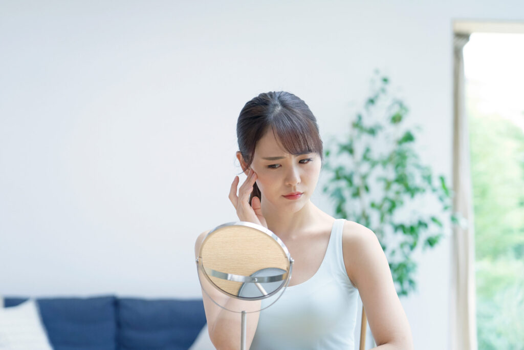 鏡の前で顔に手を添える女性