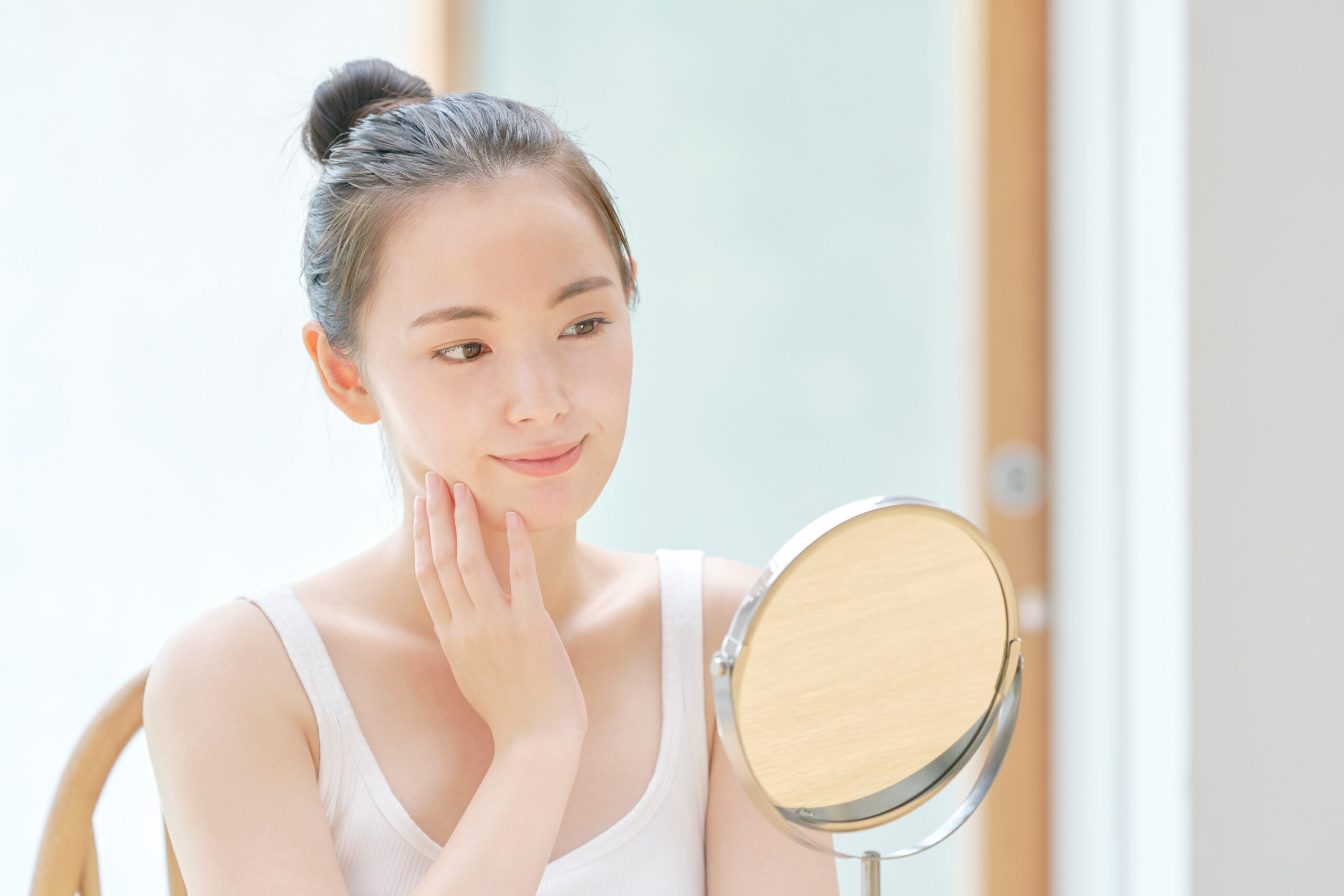 鏡の前で顔に手を添える女性